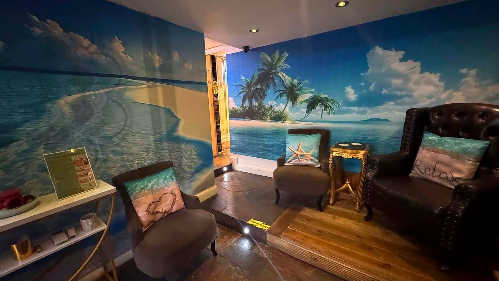 The Taitam-D waiting area, with a painted beach mural, armchairs and a low table