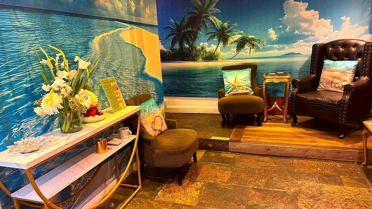 The waiting lounge with a wall-to-wall painted tropical beach, leather armchairs and a console table
