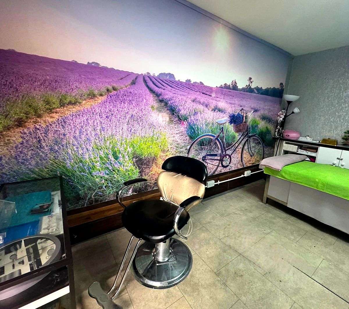 A salon styling chair in front of a wall-length photographic mural of a lavender field with a bicycle