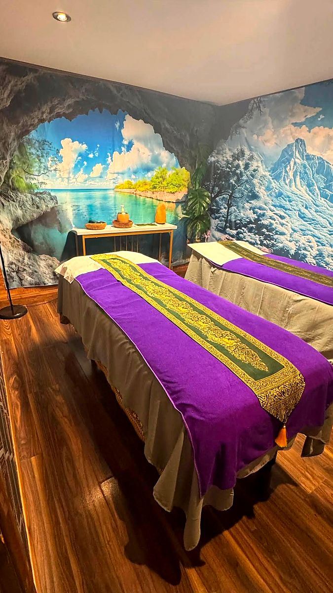 The couples' Thai massage room with twin beds, purple covers and gold Thai silk runners