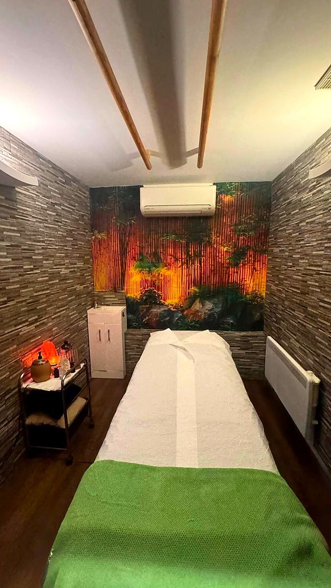 A treatment room with a stone wall and a mural of an autumn forest behind the bed